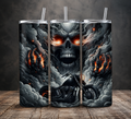 Three tall insulated tumblers with clear straws are shown standing on a wooden surface against a dark gray wall. The tumblers feature a dramatic black, gray, and white smoky graphic with glowing orange-red eyes on a skull, flaming clouds, and a motorcycle illustration.