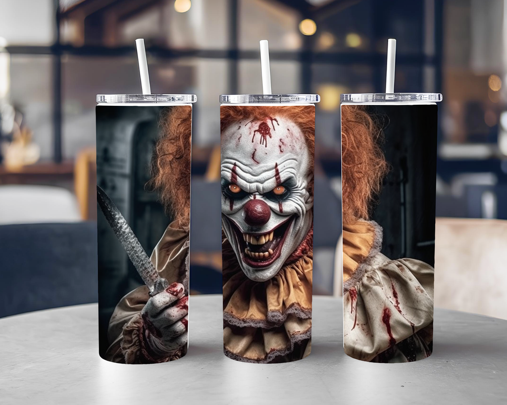 Three tall insulated tumblers with clear lids and white straws, each printed with a horror clown design, displayed on a tabletop in a blurred indoor setting.