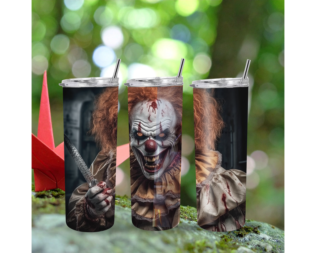 Three tall insulated tumblers with clear lids and metal straws, printed with a horror clown design, shown against a blurred green outdoor background with a red origami crane on the left.
